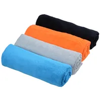 Quatro toalhas de veludo enroladas, em azul, cinzento, laranja e preto
