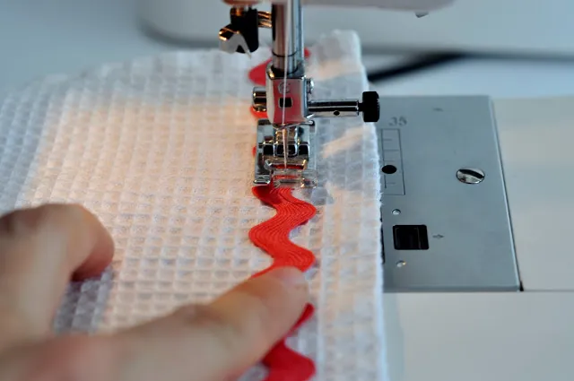 Sewing a red trim onto white waffle fabric