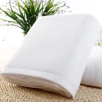 Toalla de baño blanca de gran tamaño, con cenefa de vainica, doblada sobre una esterilla trenzada
